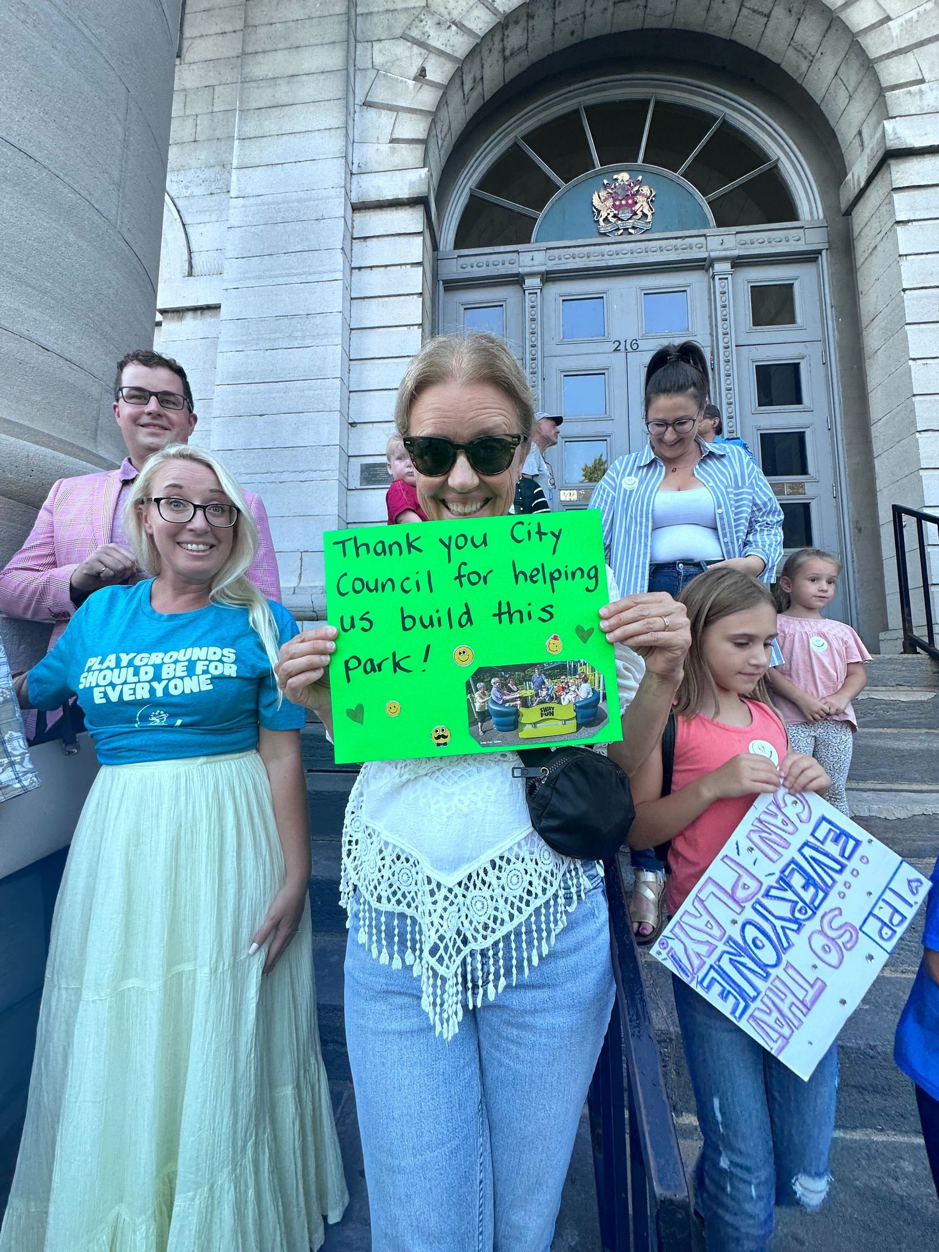 A group of people are standing in front of a building holding signs.