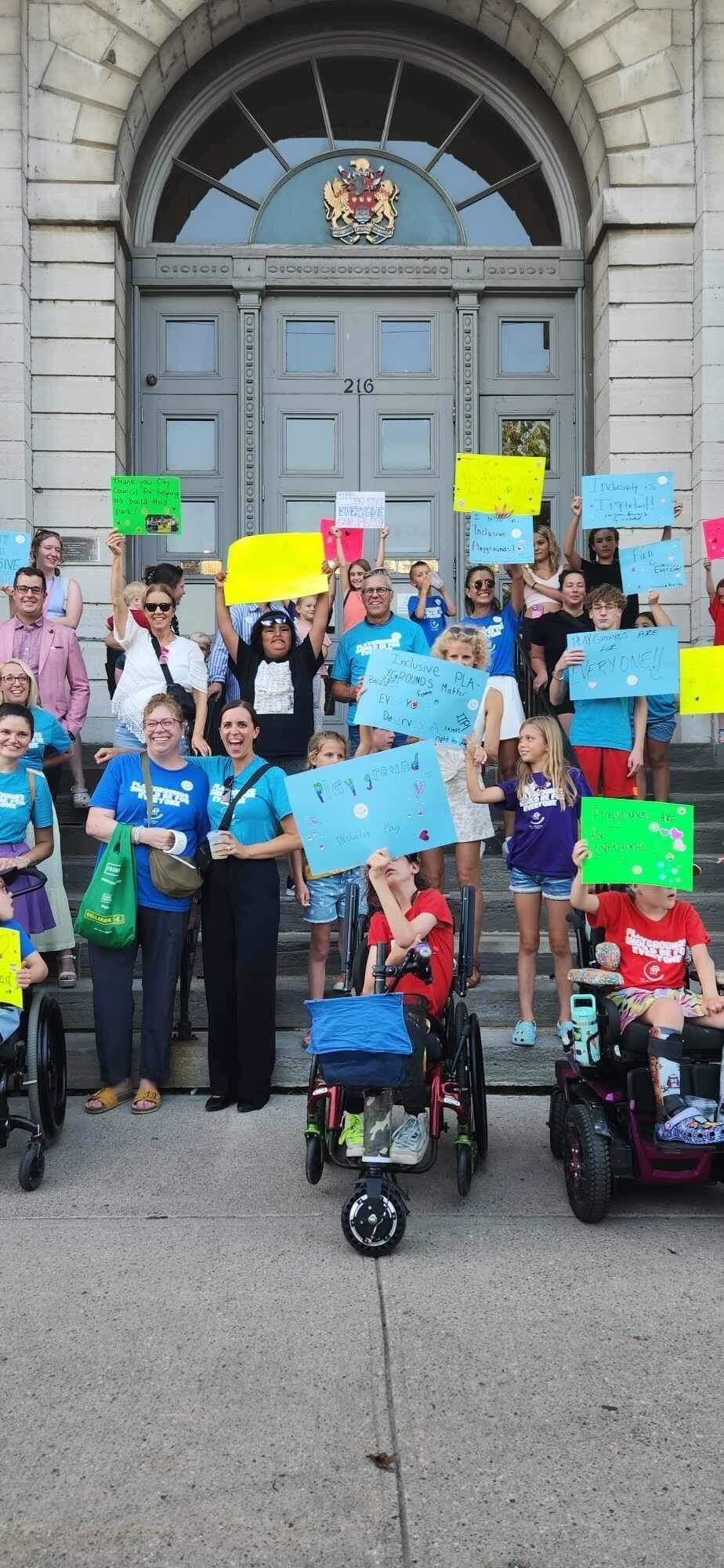 A group of people are standing in front of a building holding signs.