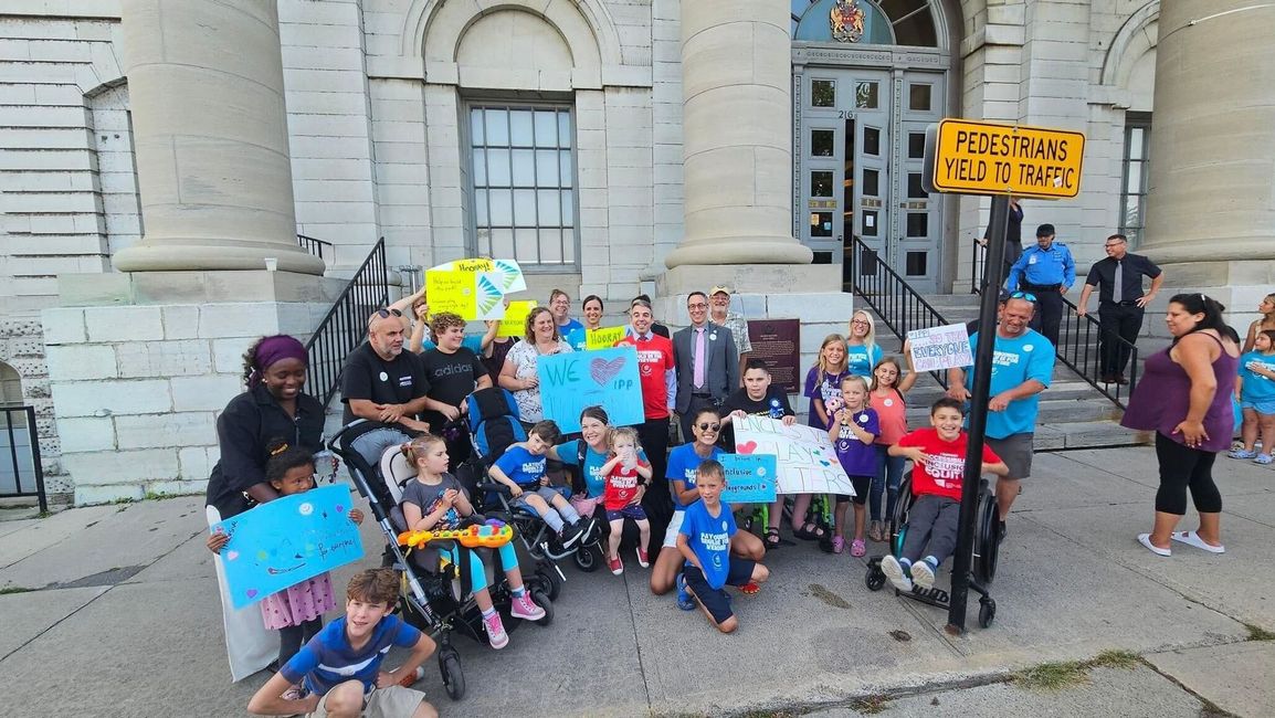 A group of people are standing in front of a building holding signs.