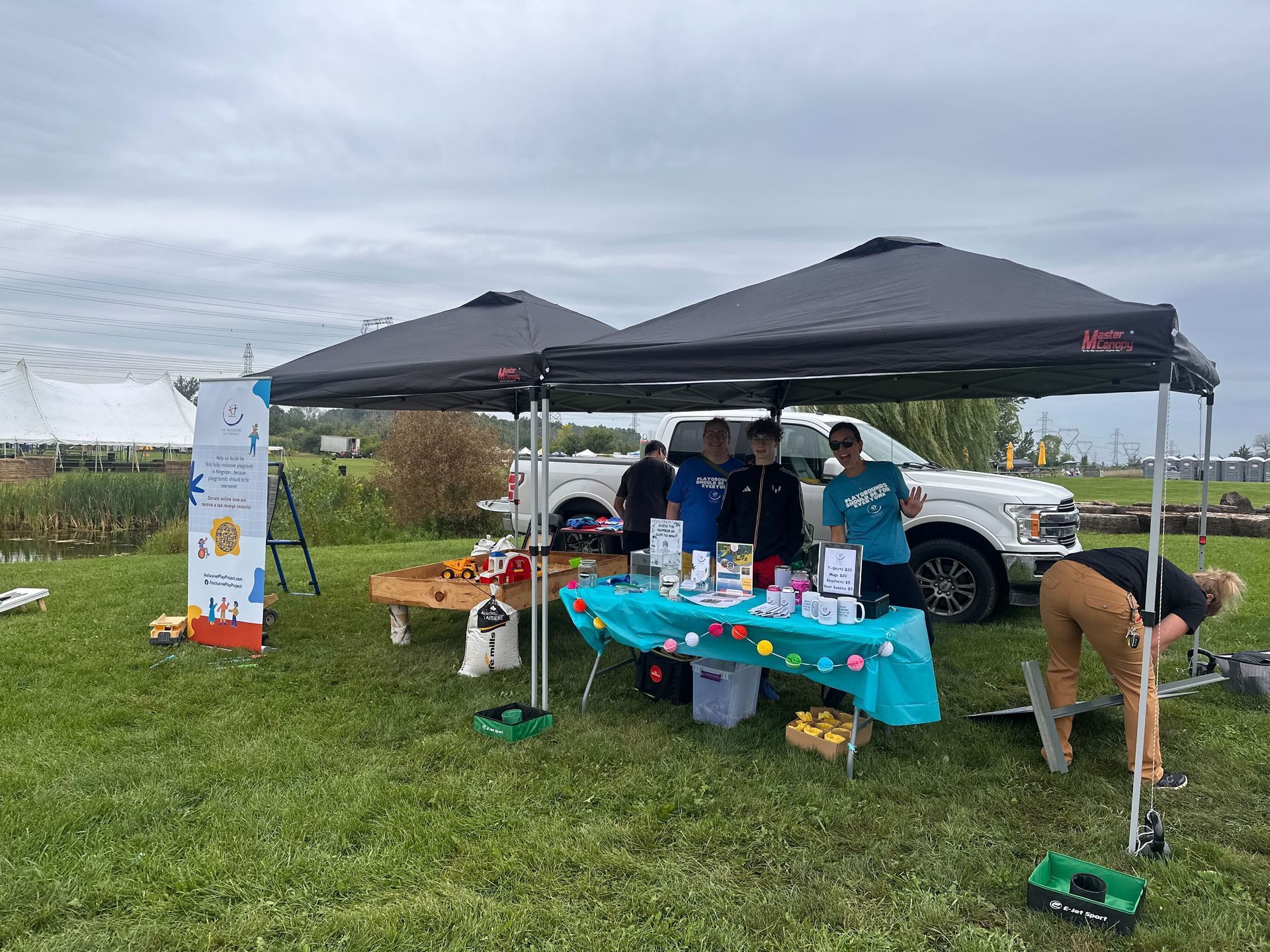A group of people are standing under a tent in a field.