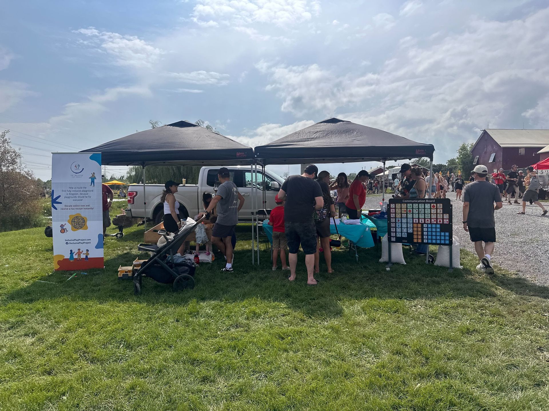 A group of people are standing around a table under a tent in a field.
