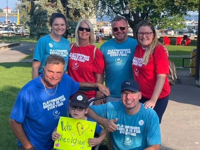 A group of people are posing for a picture and one of them is holding a sign that says we love everyone