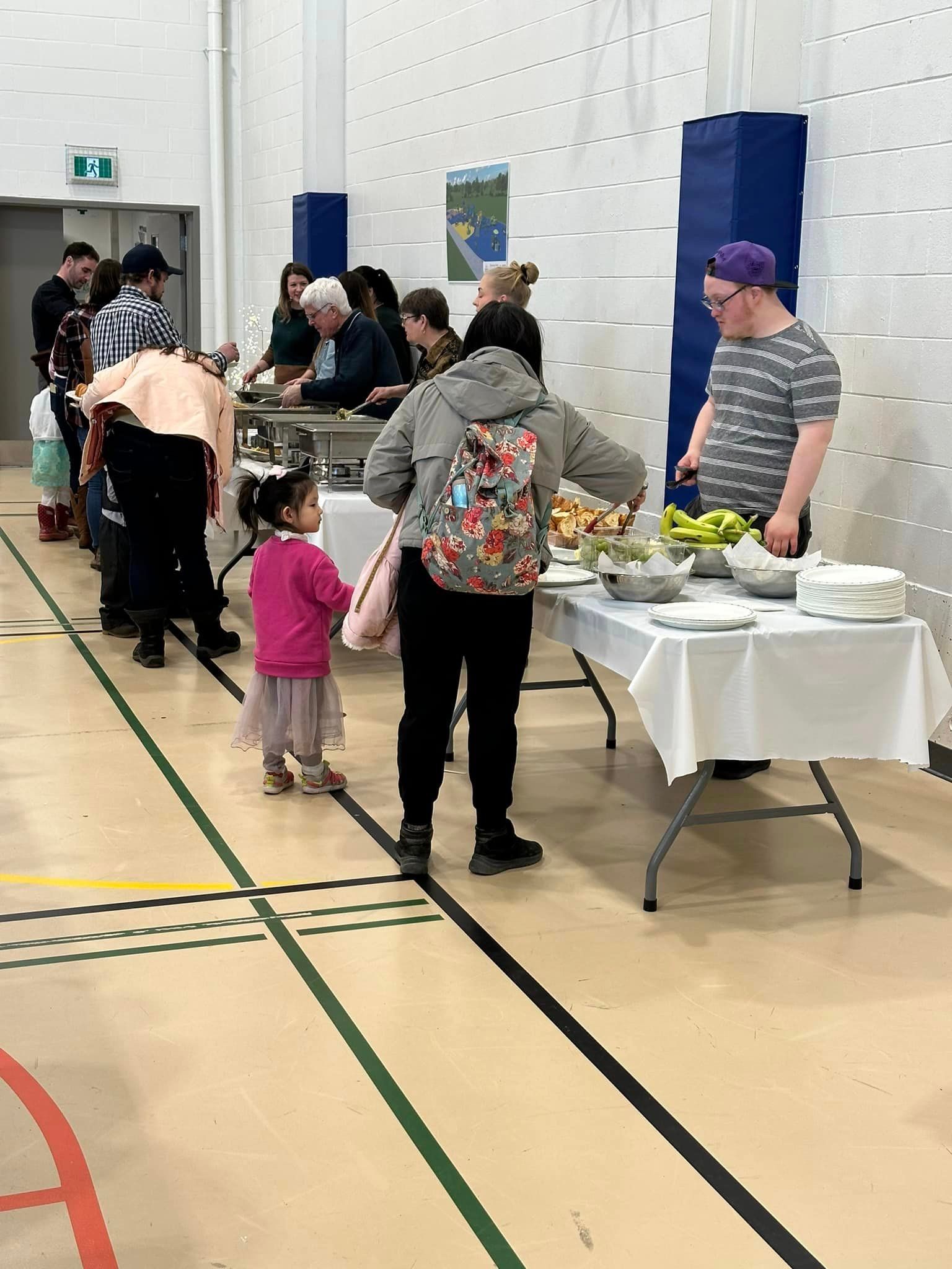 A group of people are standing around a table in a gym.