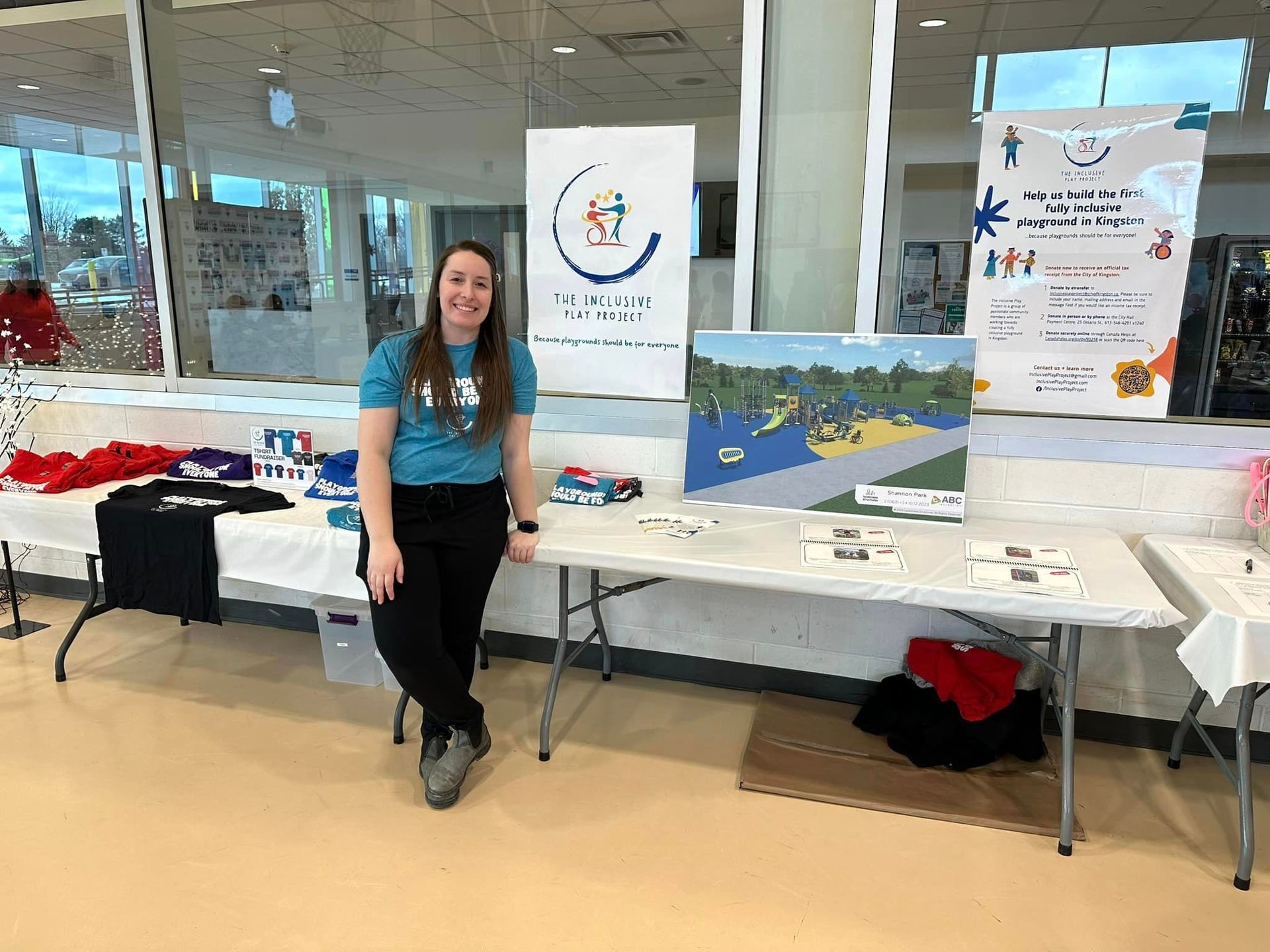A woman is standing next to a table with a painting on it.