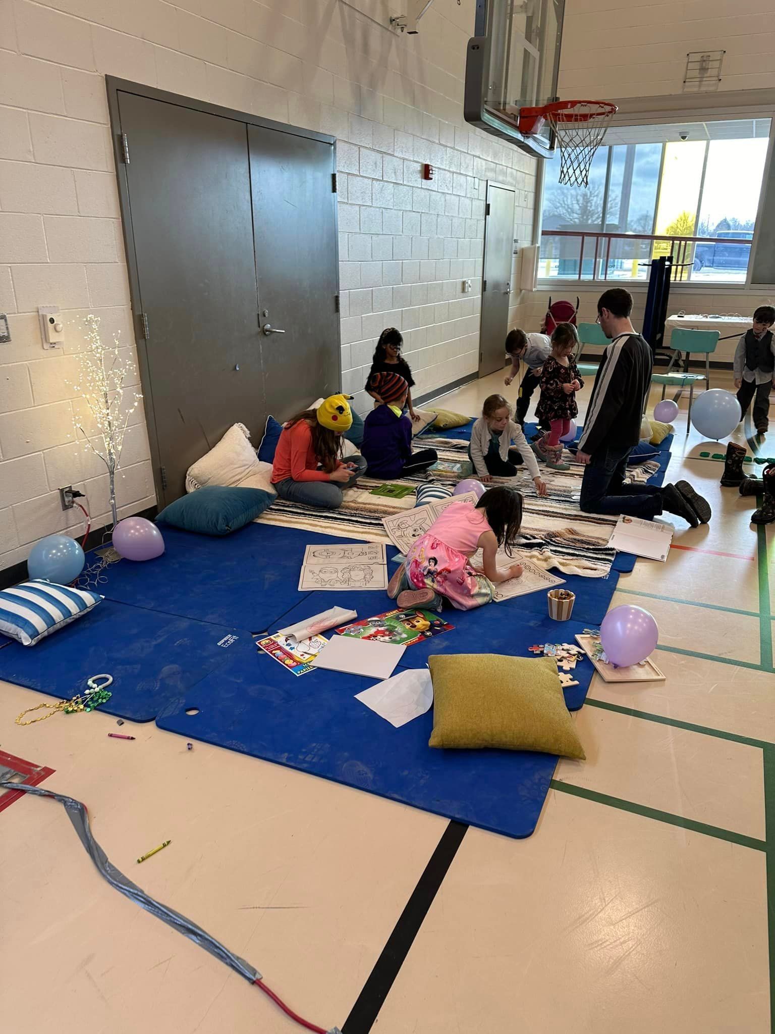 A group of children are sitting on the floor in a gym.