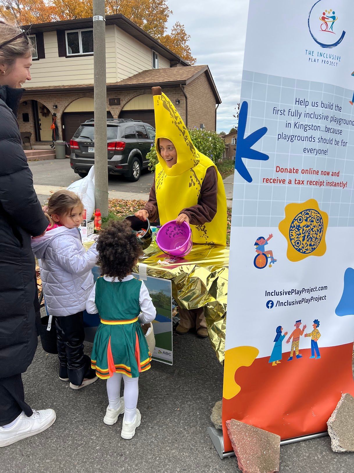 A woman in a banana costume is sitting at a table with children.