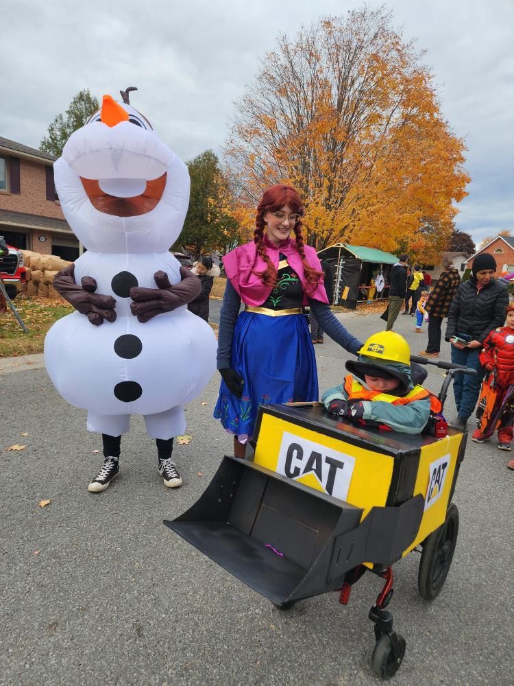 A woman in a frozen costume is standing next to a child in a cat costume.