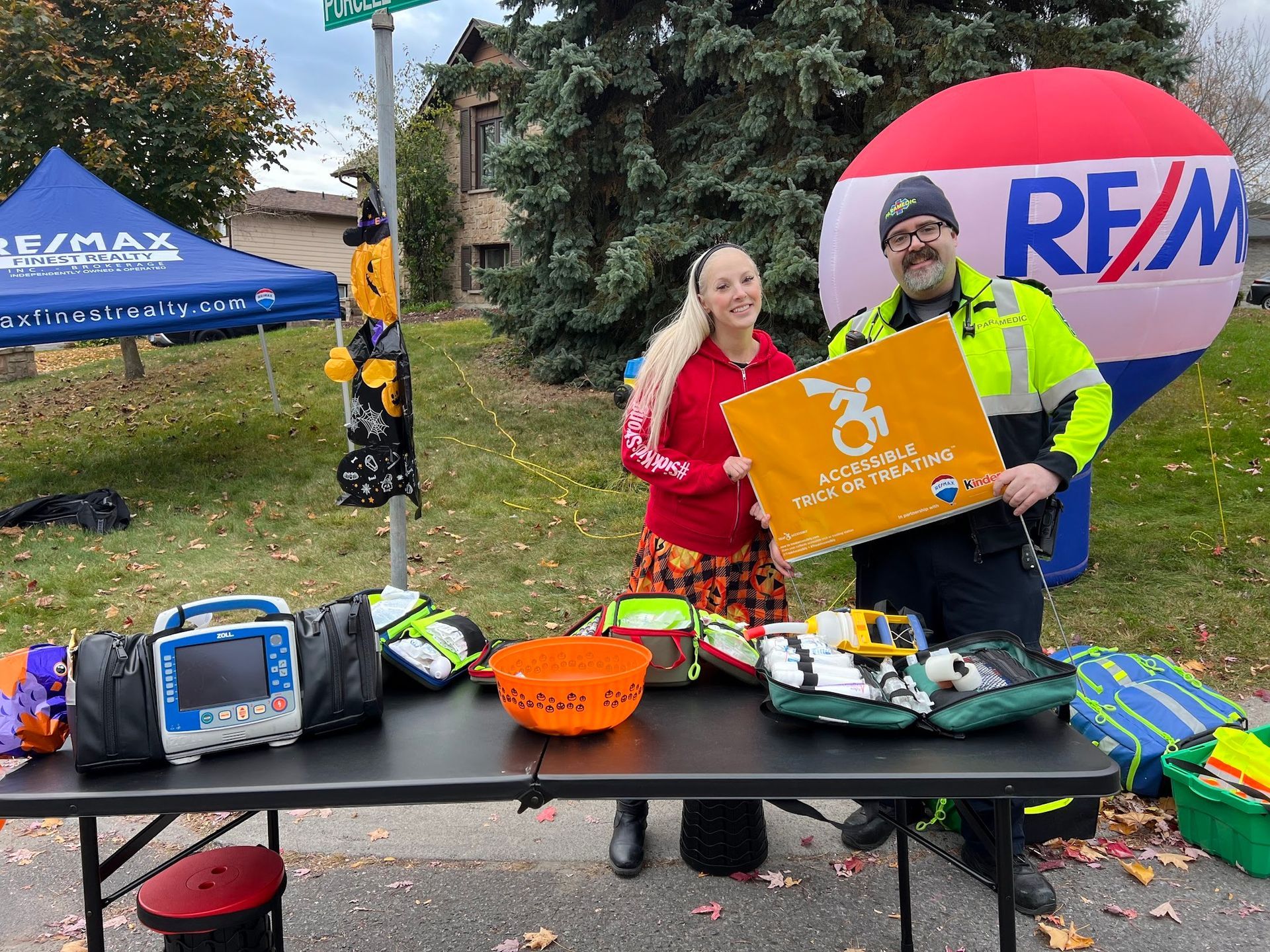 A man and a woman are standing next to a table holding a sign.