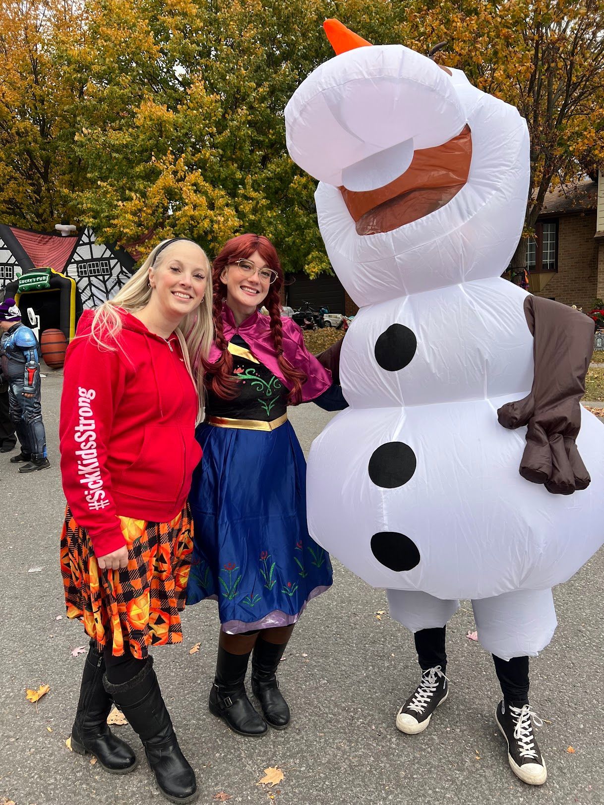 Two women are posing for a picture with an inflatable snowman.