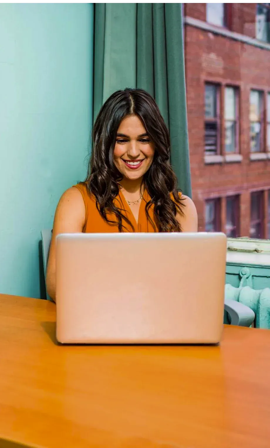 Uma mulher está sentada à mesa usando um laptop.