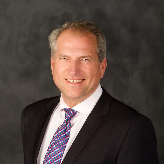 A man in a suit and tie is smiling for the camera.