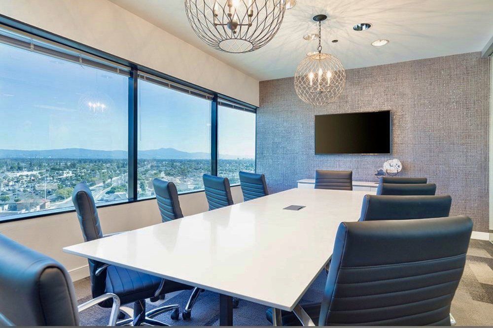 A conference room with a long table and chairs and a flat screen tv.