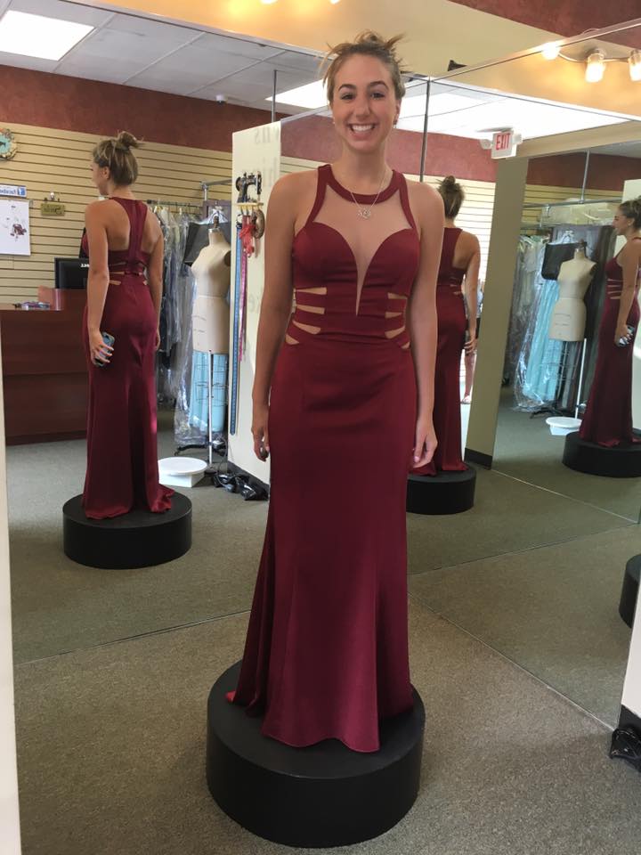 A woman is trying on a red dress in a store.