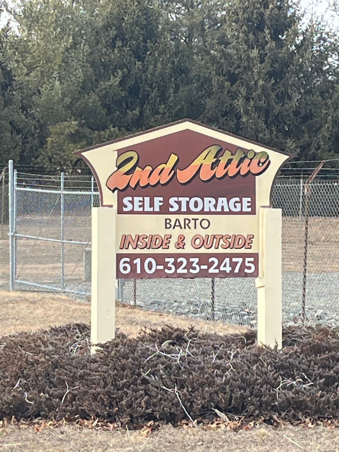 A sign for a self storage facility with a fence in the background.
