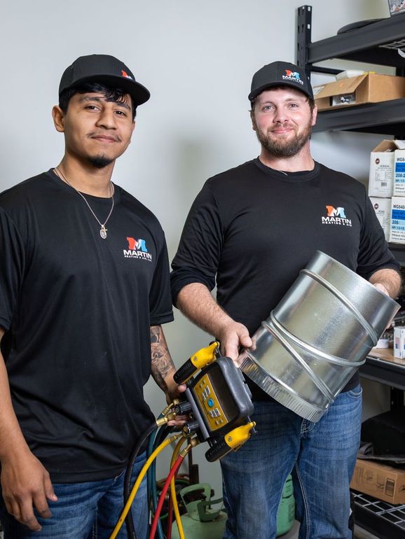 martin heating and air technicians are standing next to each other in front of a brick building.