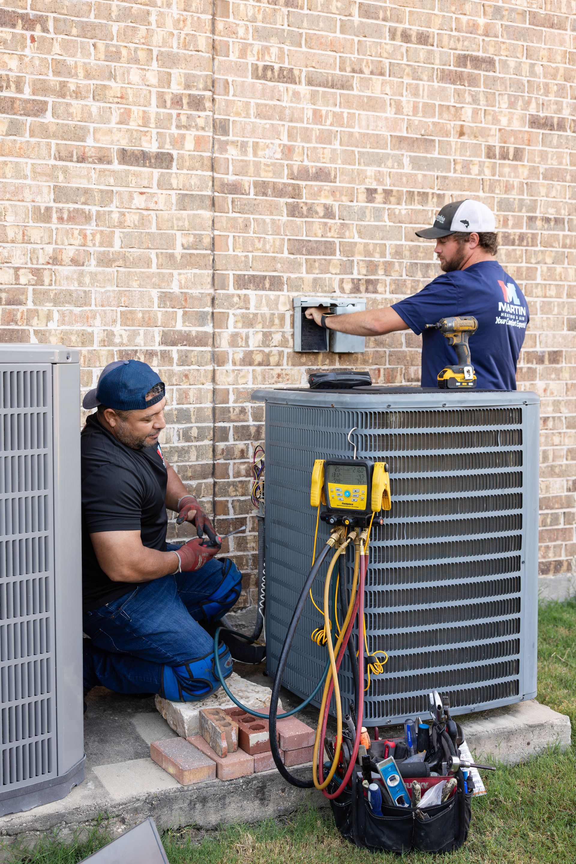 Two air conditioners are sitting on the side of a house.