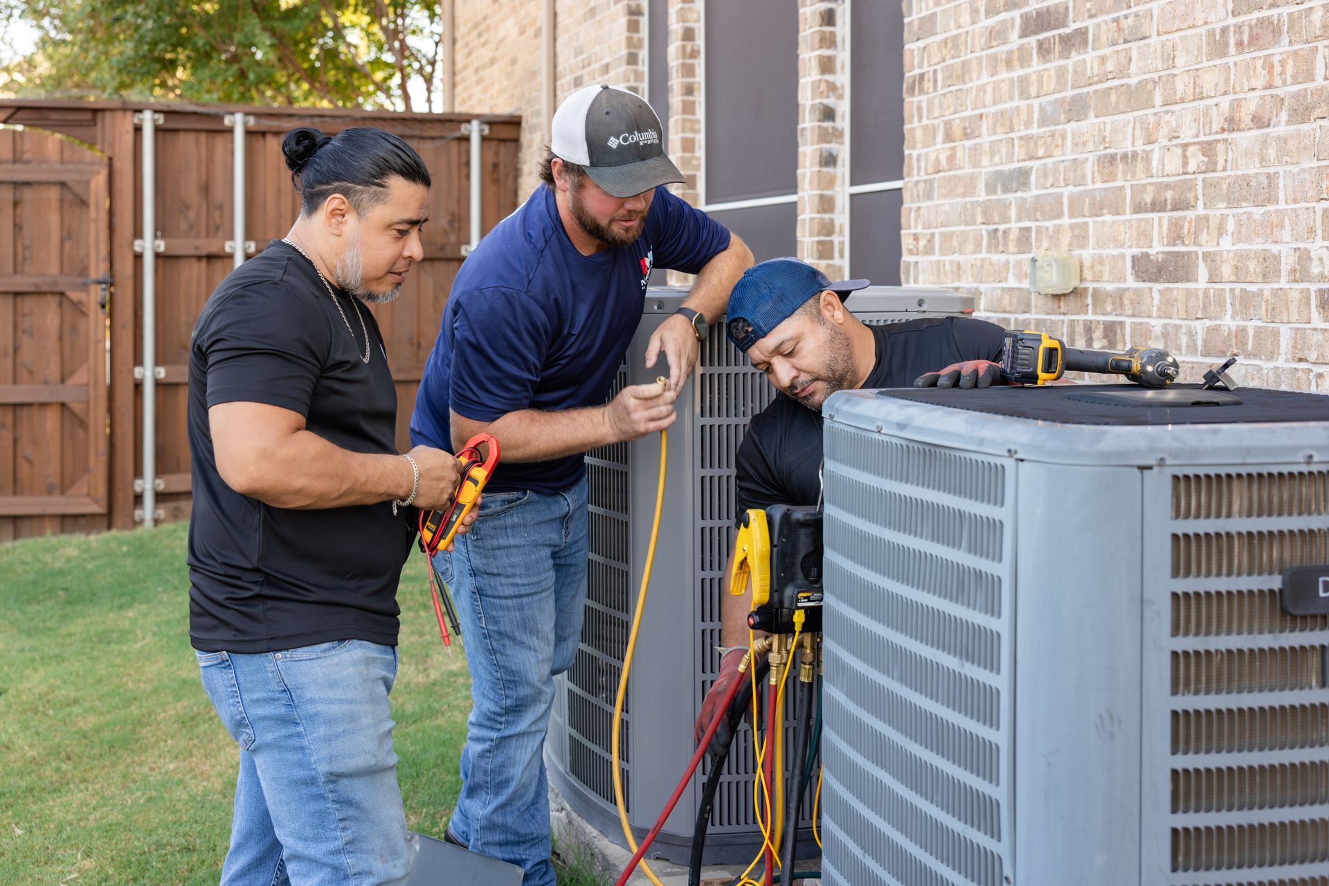 A man is working on an air conditioner while looking at a tablet.