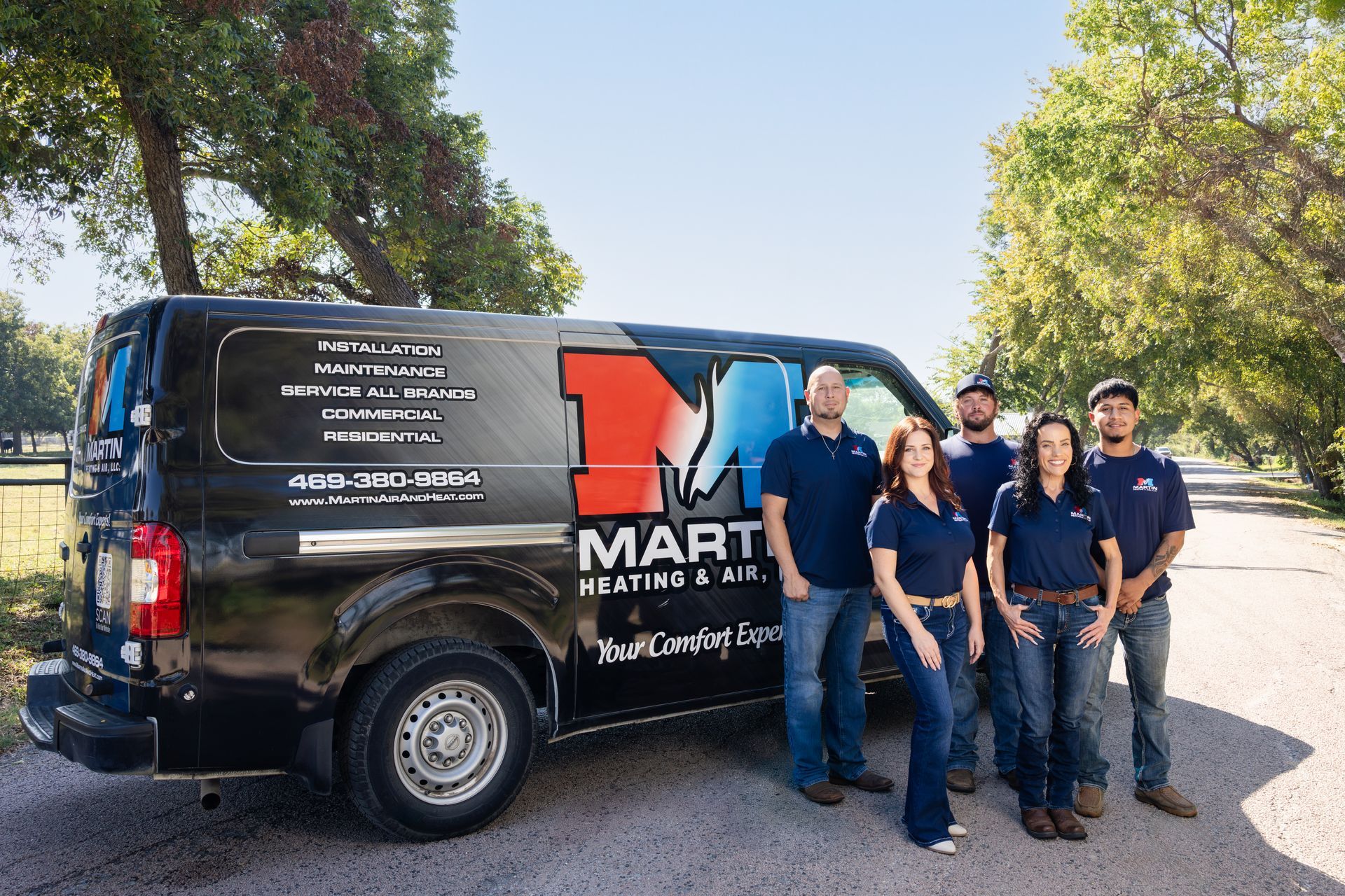 A man is sitting on the floor working on an air conditioner.