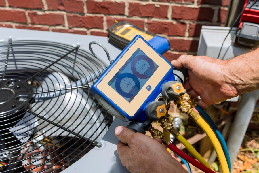 A man is working on an air conditioner outside of a brick building.