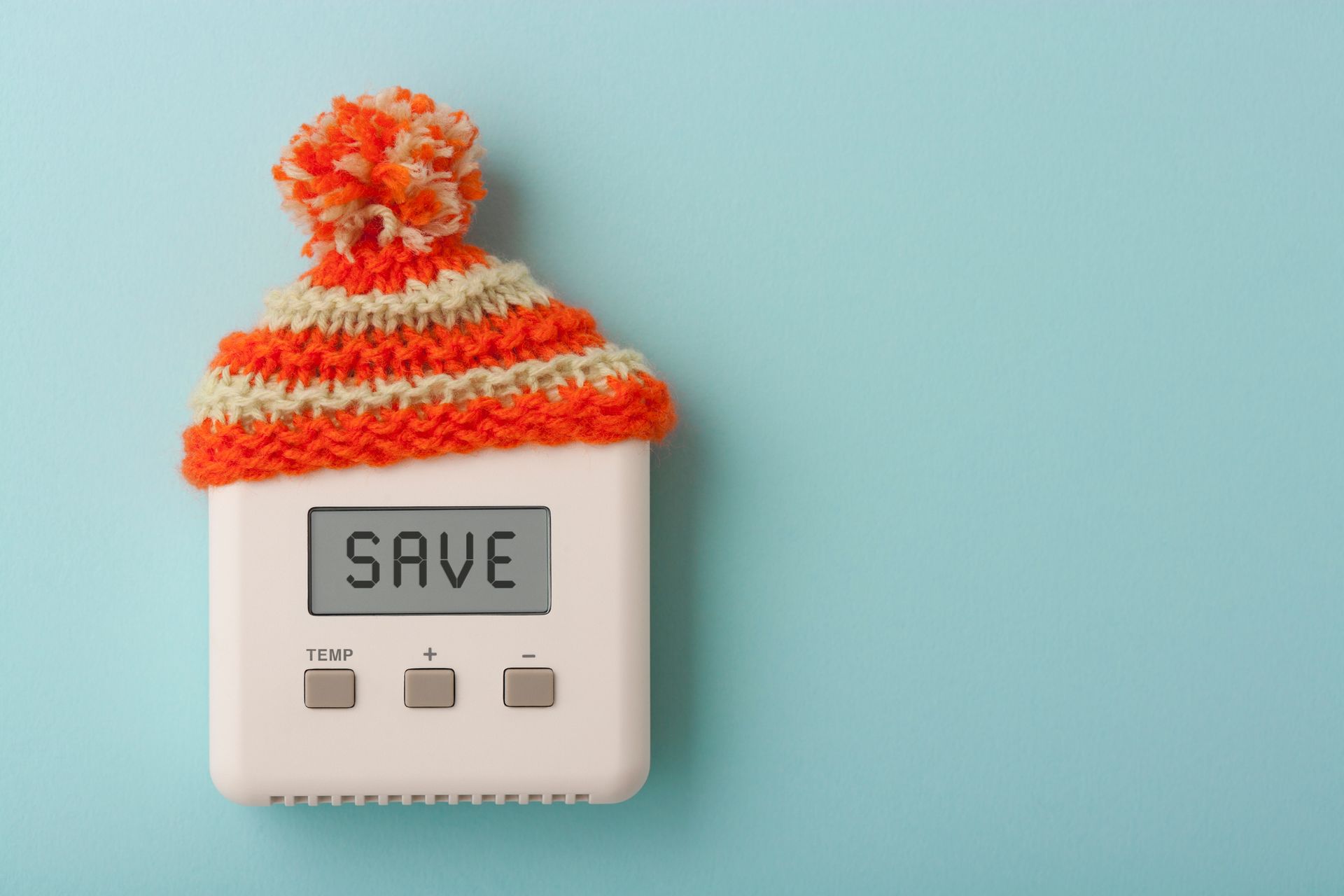 A thermostat with SAVE on the display with a knitted beanie on top.