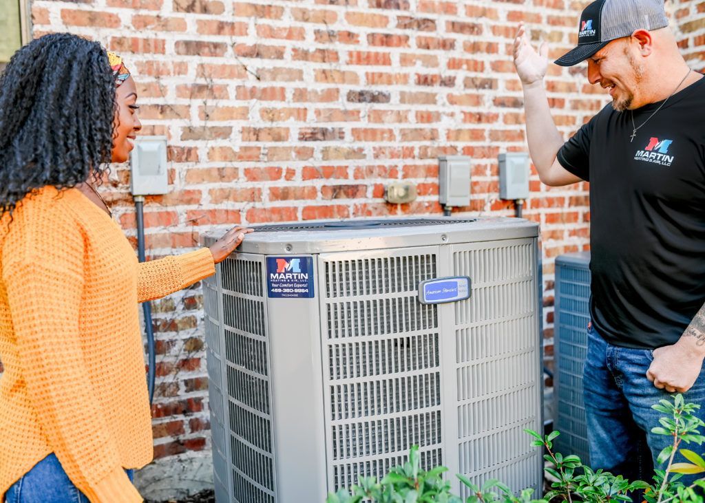 A man and a woman are standing next to an air conditioner.