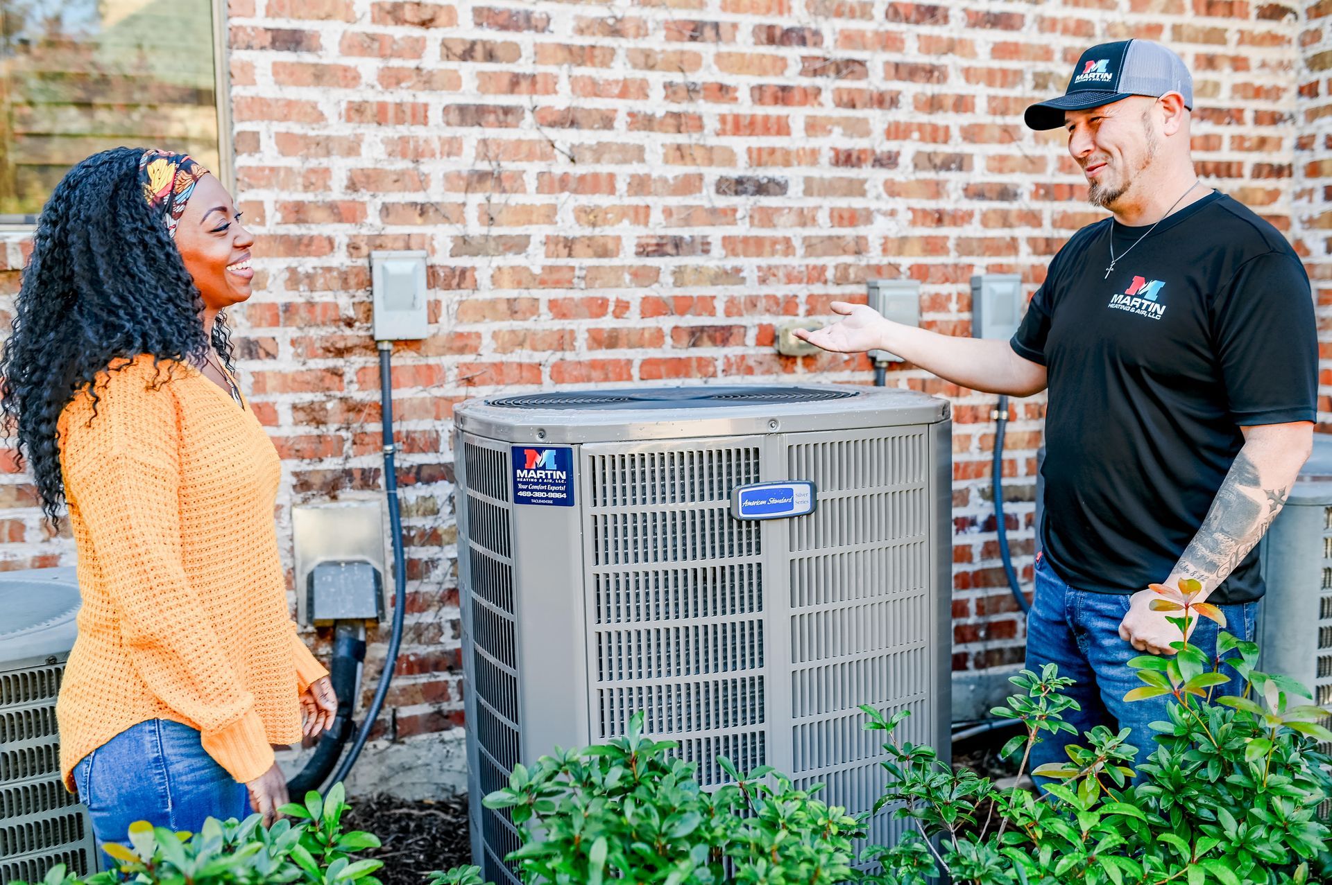 A man is talking to a woman in front of an air conditioner.