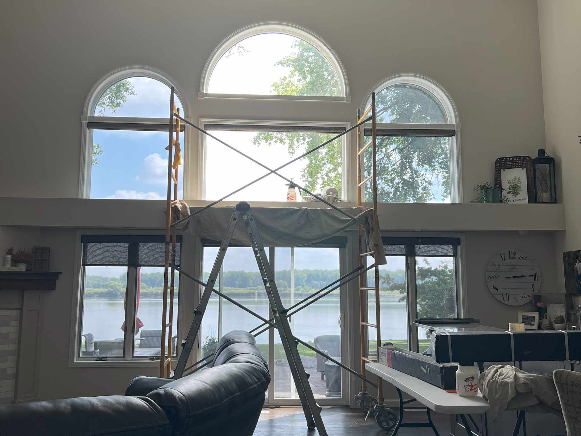 A living room with a lot of windows and a ladder in the middle of the room.
