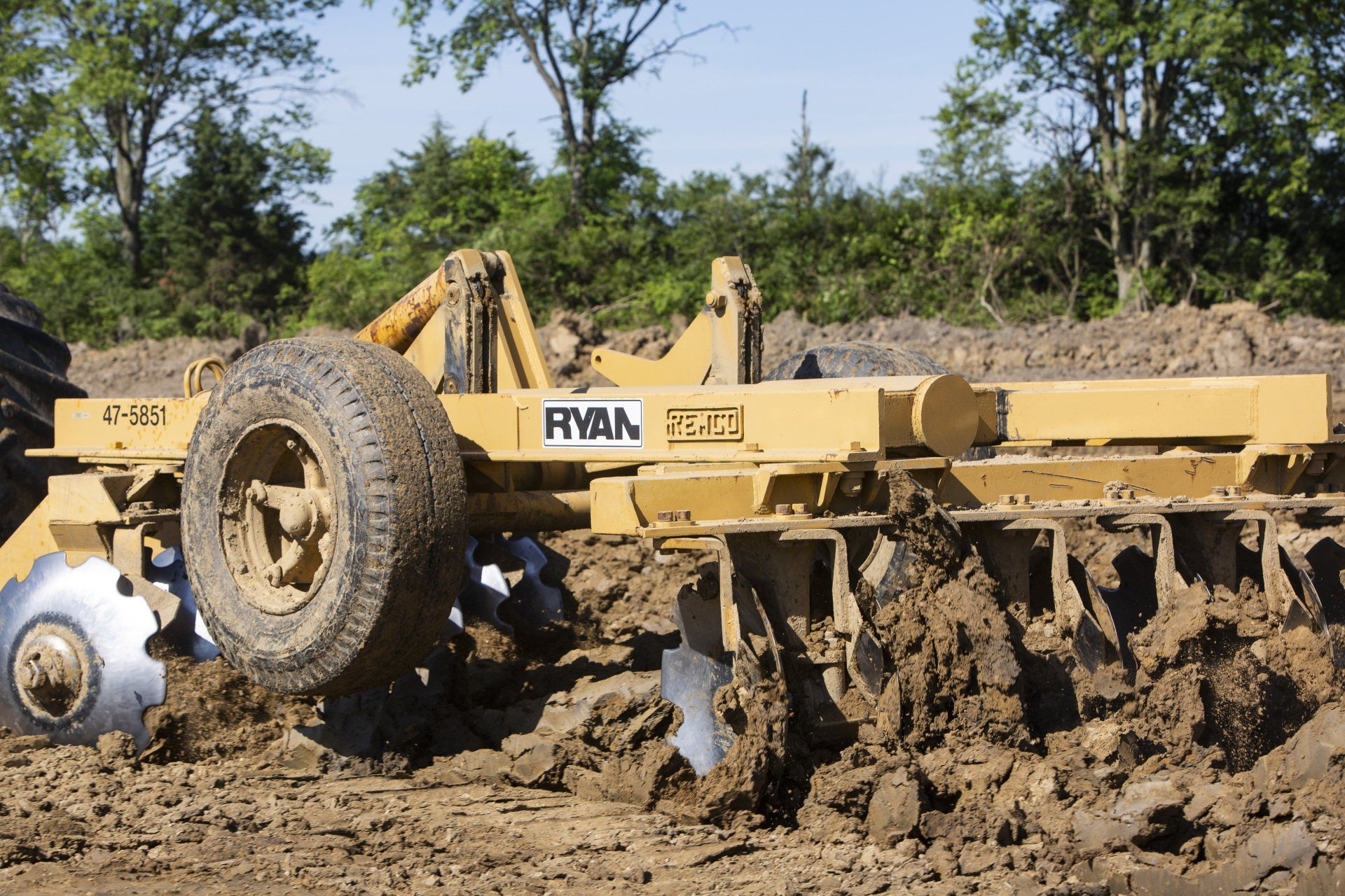 A yellow ryba plow is driving through a muddy field