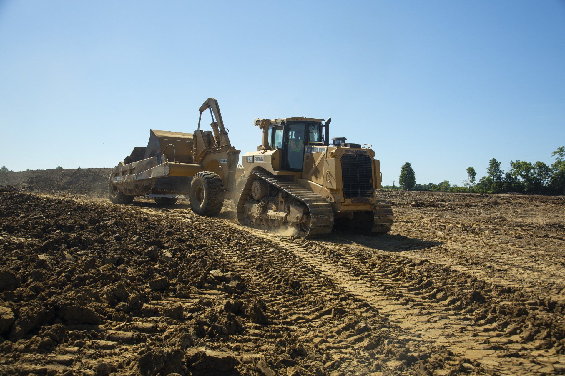 A bulldozer is driving through a dirt field.