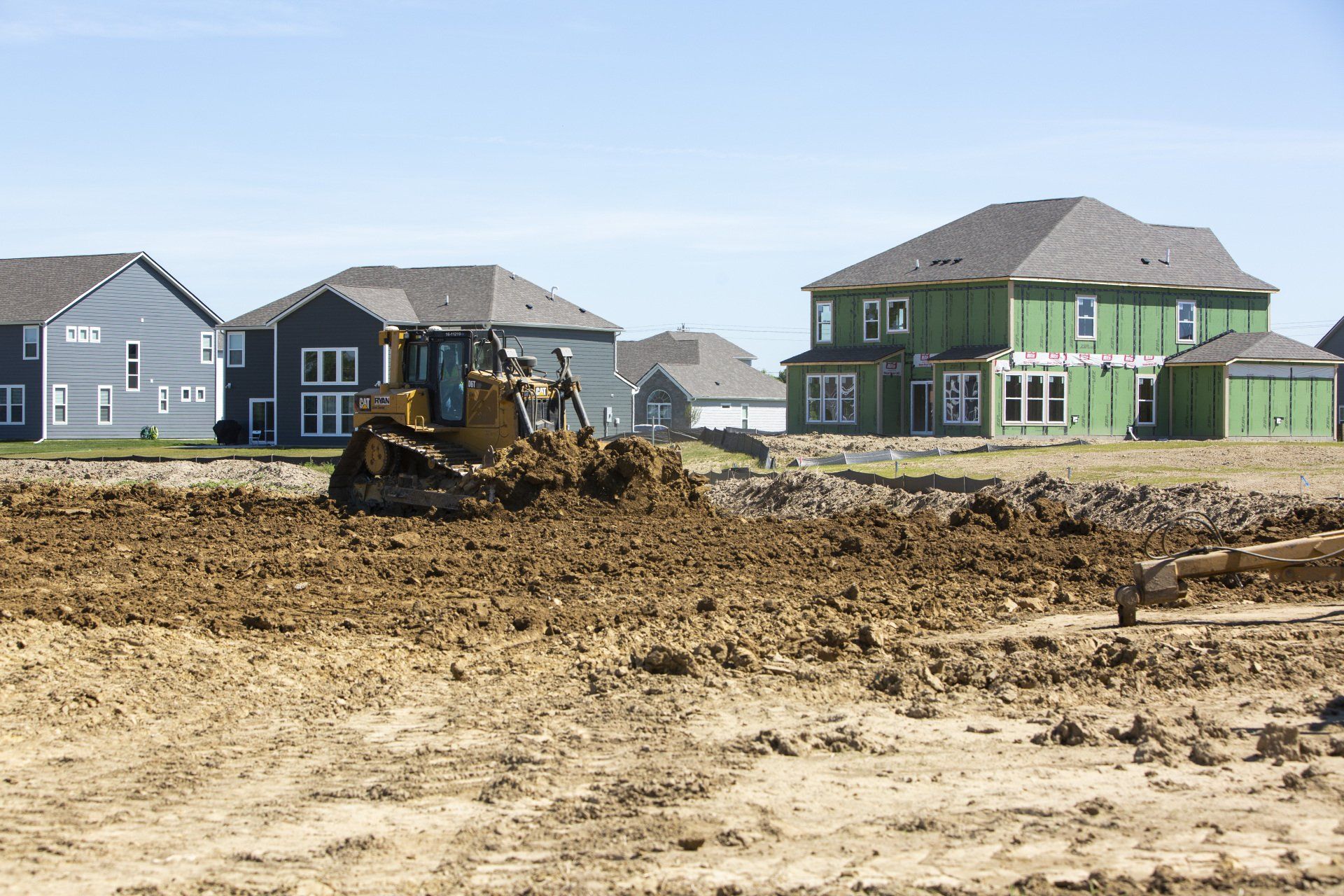 A bulldozer is moving dirt in front of a row of houses.