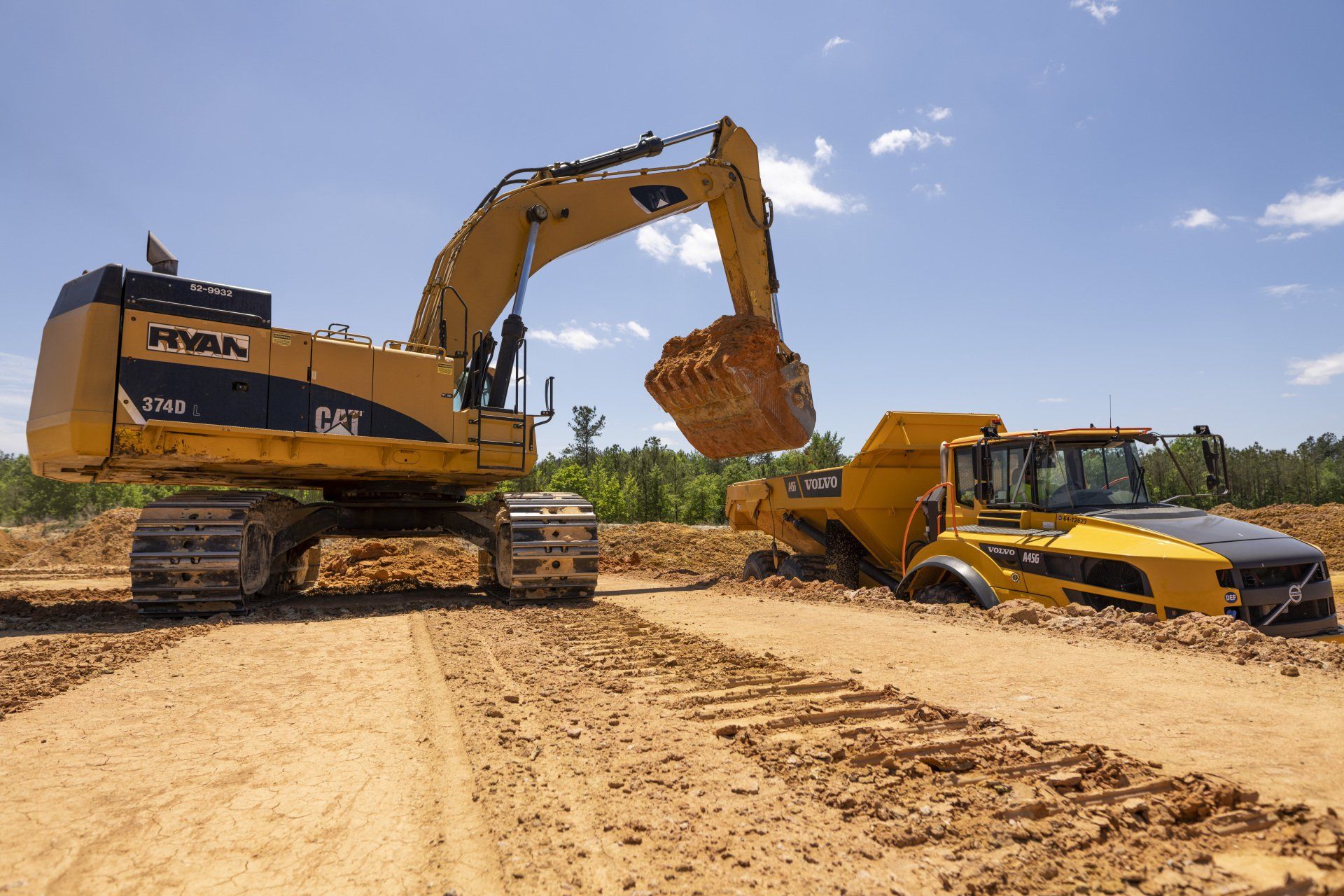 A cat excavator is loading dirt into a dump truck