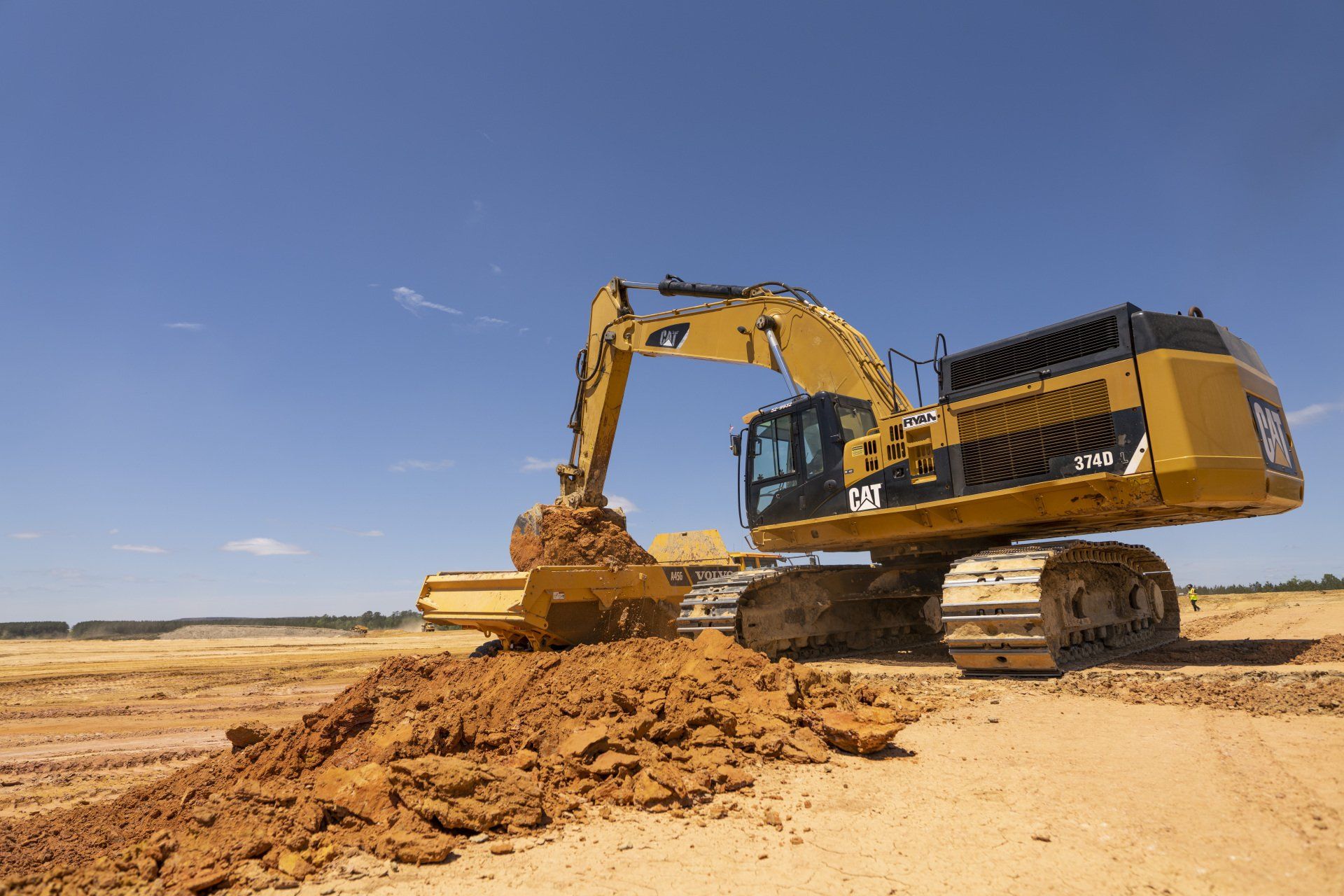 A large excavator is digging a pile of dirt on a construction site.