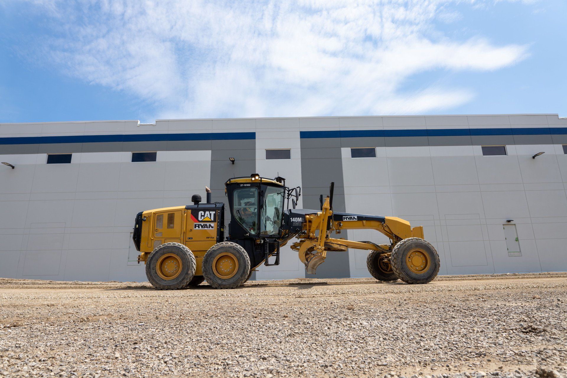 A yellow and black tractor is parked in front of a building.