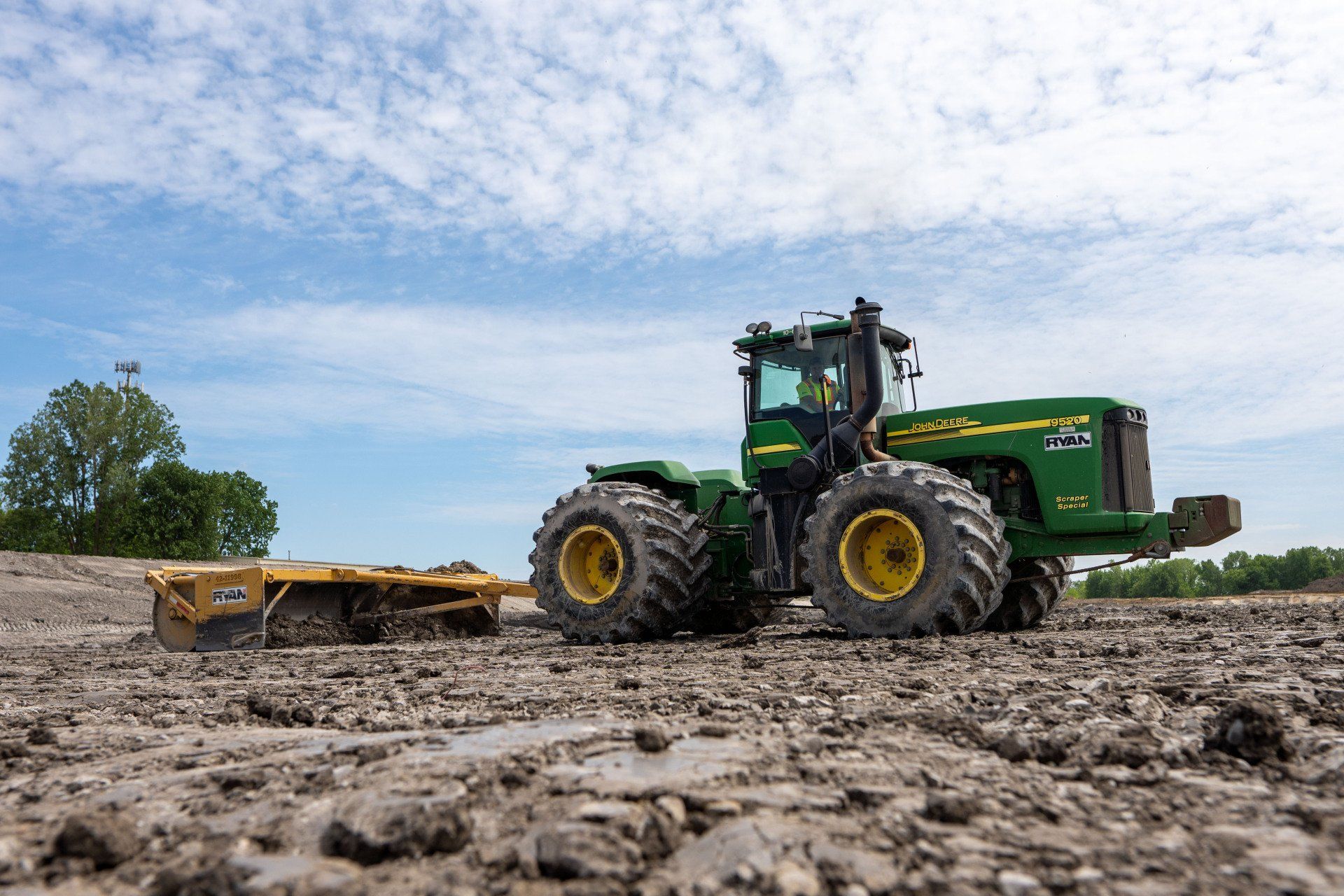 A john deere tractor is driving through a muddy field.