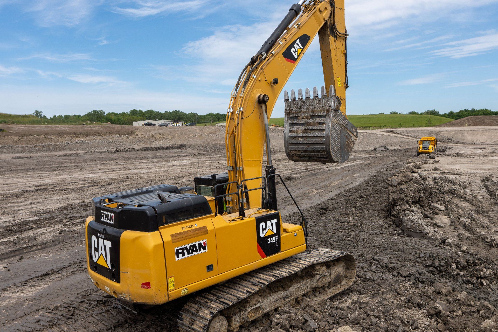 A large yellow excavator is driving through a muddy field.