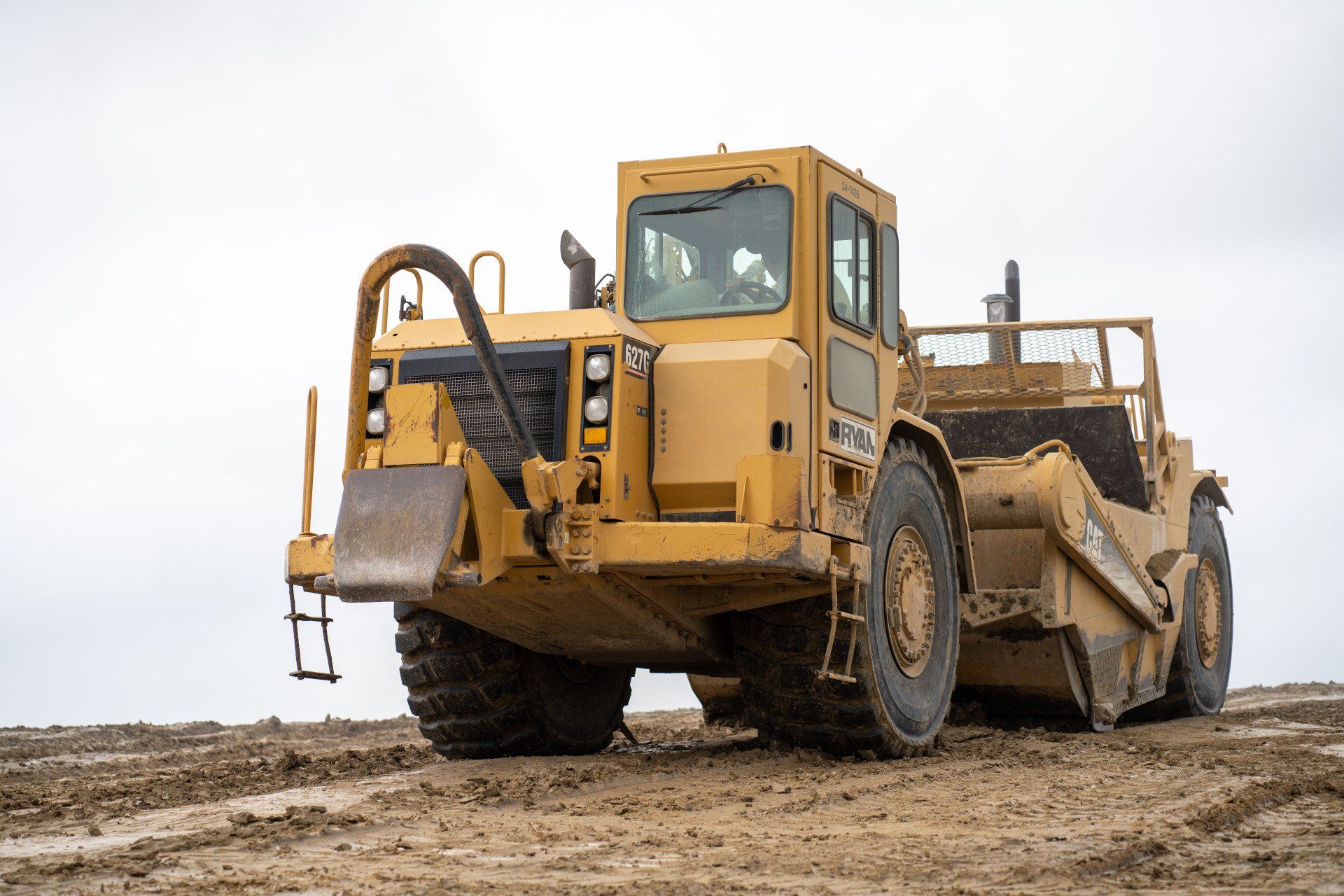 A yellow bulldozer is sitting on top of a dirt field.