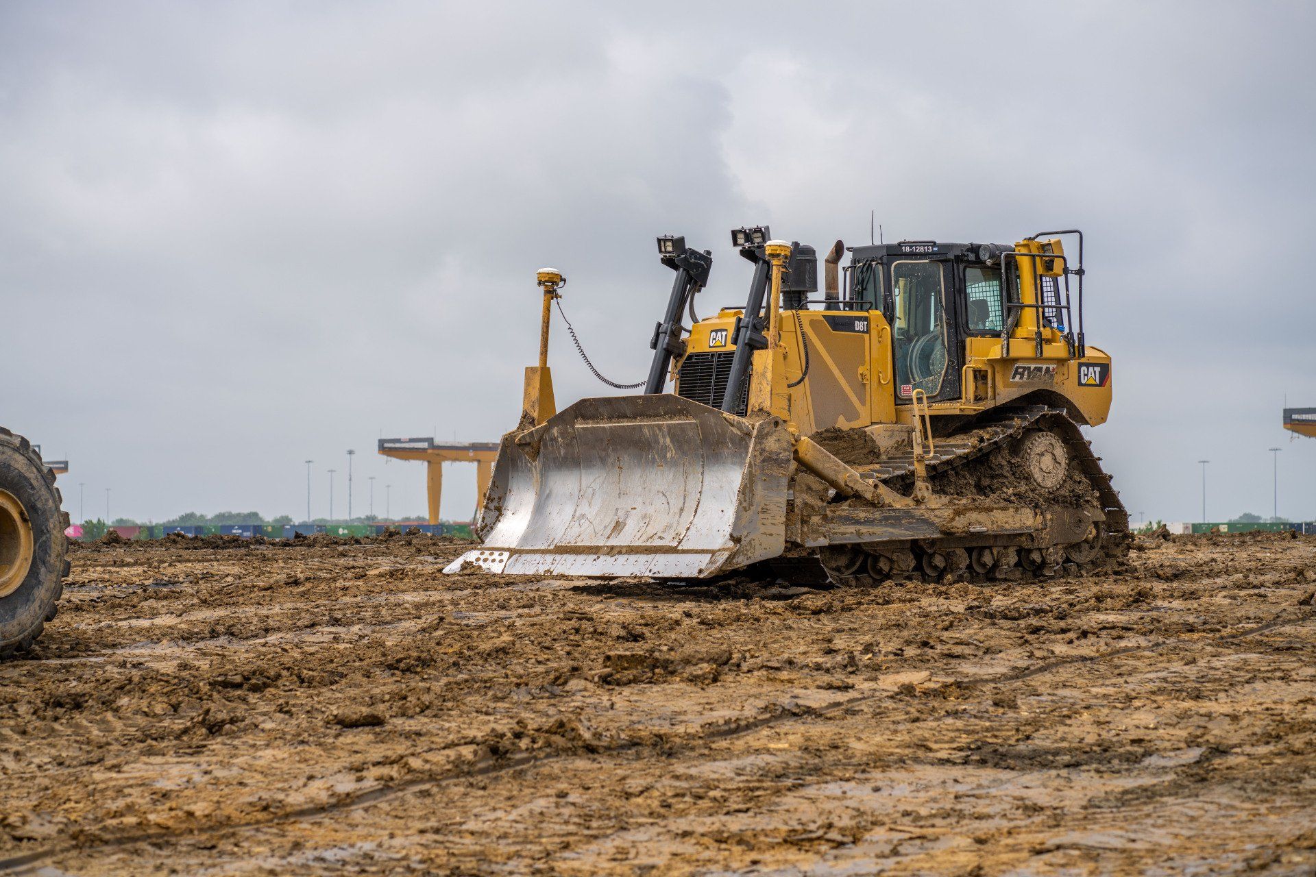 A bulldozer is driving through a muddy field.