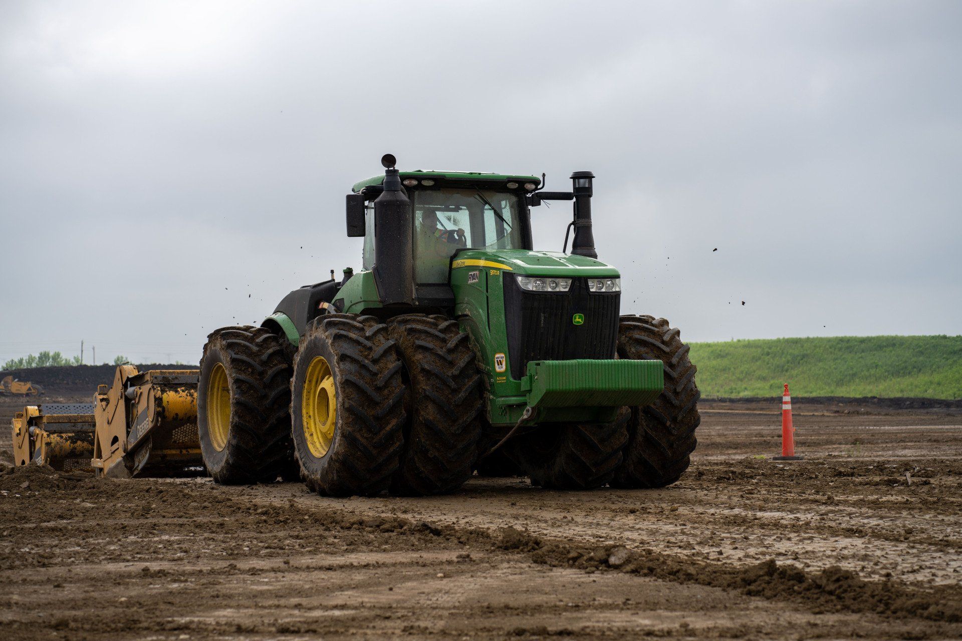 A green john deere tractor is plowing a dirt field.