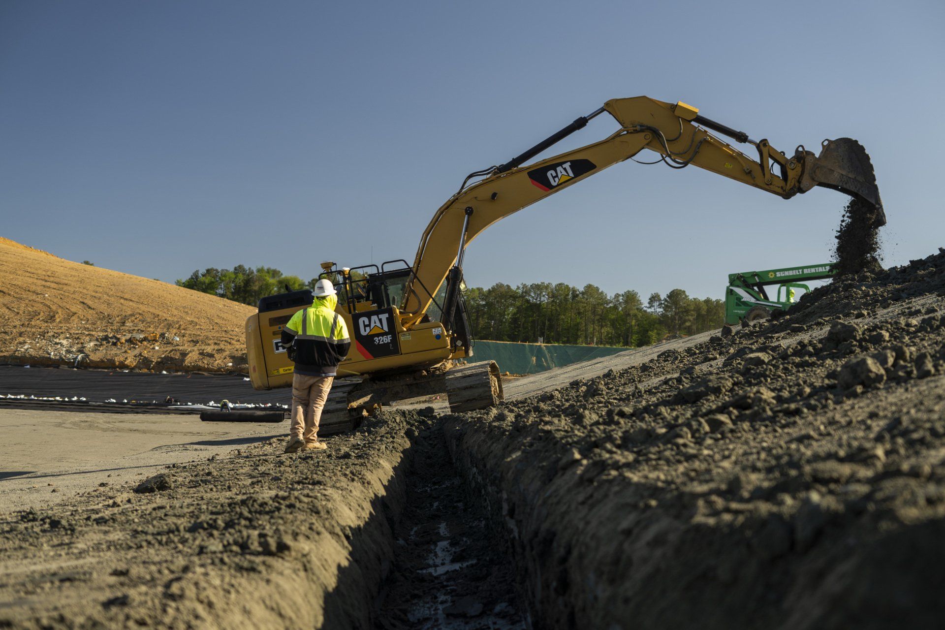 A cat excavator is digging a hole in the ground.