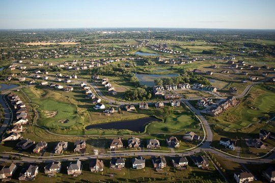 An aerial view of a residential area with lots of houses and a golf course.