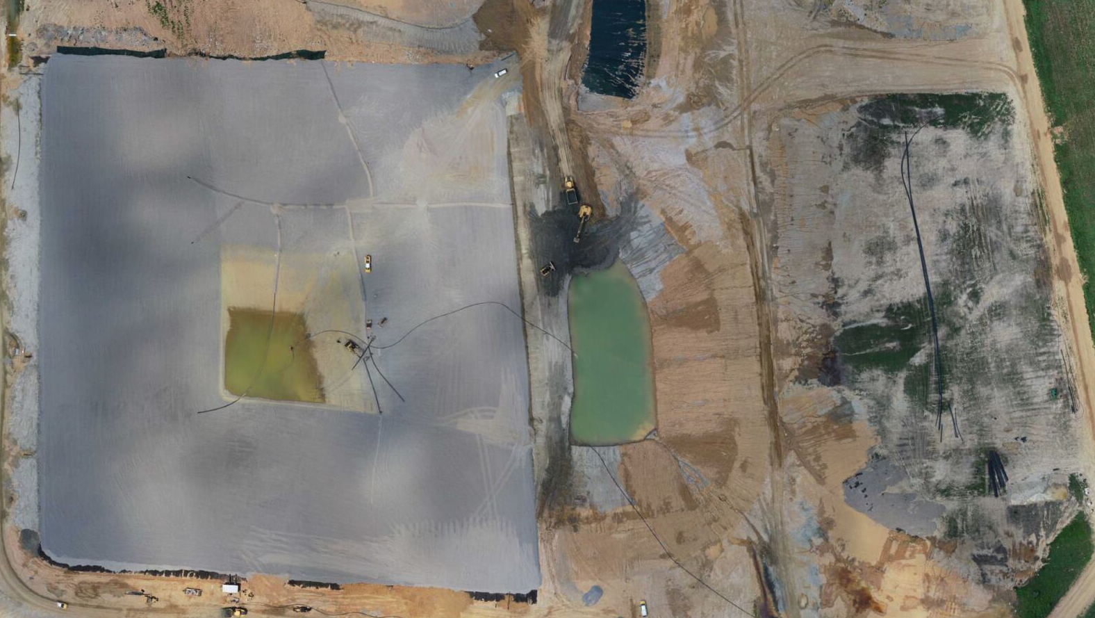 An aerial view of a large dirt field with a pond in the middle.