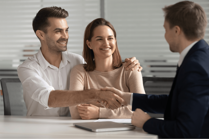 A man and woman are shaking hands with a man in a suit.