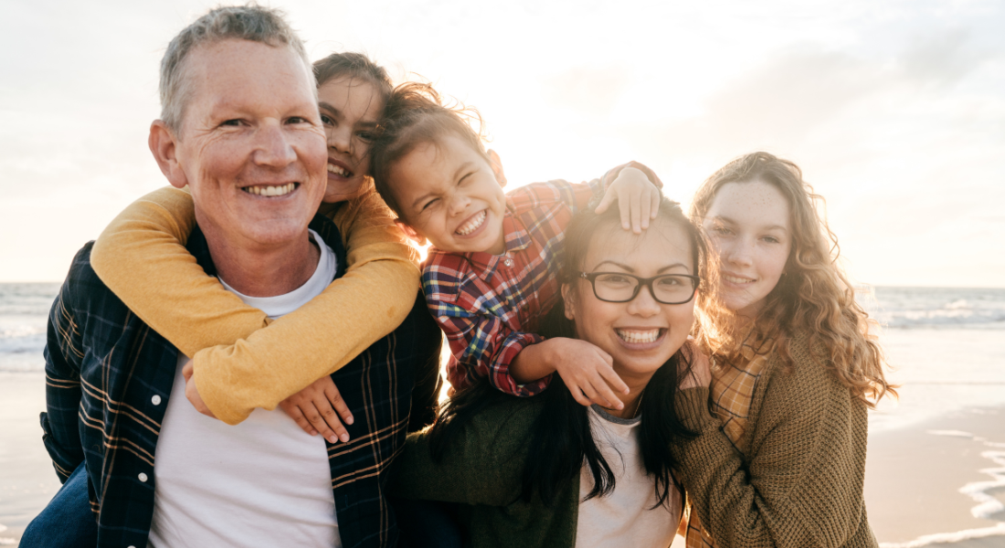 A family is posing for a picture on the beach.