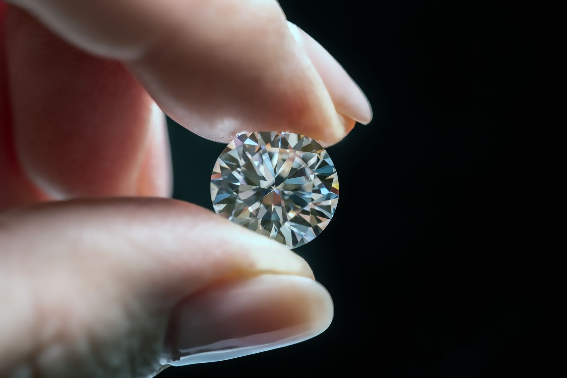 Woman's hand holding a diamond, showcasing cash for diamonds services with sparkle and care.