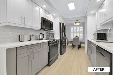 Modern kitchen with white upper cabinets, gray lower cabinets, and black appliances.