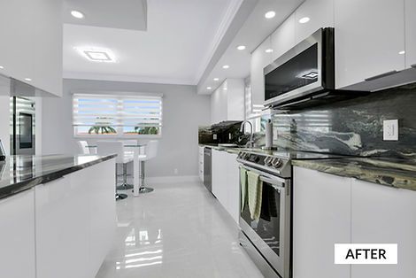 Modern white kitchen with stainless steel appliances, dark countertops, and tile flooring.