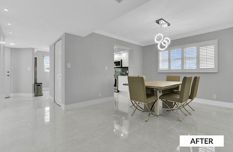A modern dining room with light gray walls, a table, and chairs, and a hallway to the left.