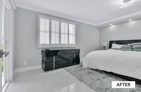 Bedroom with shutters, black dresser, large bed, gray walls, fluffy rug.
