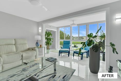 Living room with white walls, recliner, glass table, and seating area with blue chairs and large windows overlooking outdoors.