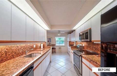 Narrow kitchen with white cabinets, speckled countertops, stainless steel appliances, and a tiled floor.